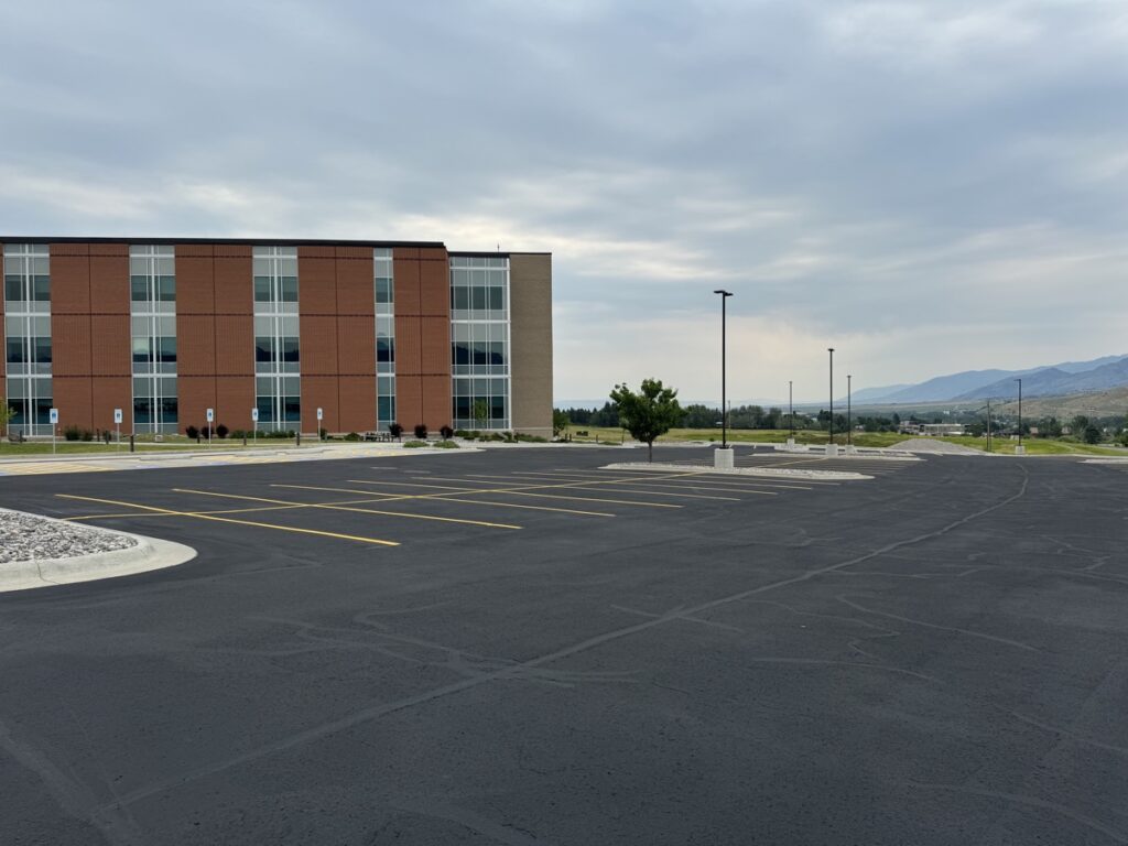 A Montana Sealcoating technician applies professional crack filling to prevent water infiltration and extend the life of asphalt surfaces through proactive maintenance.